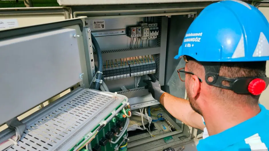 Ein Elektriker arbeitet an einem Sicherungskasten im Außenbereich