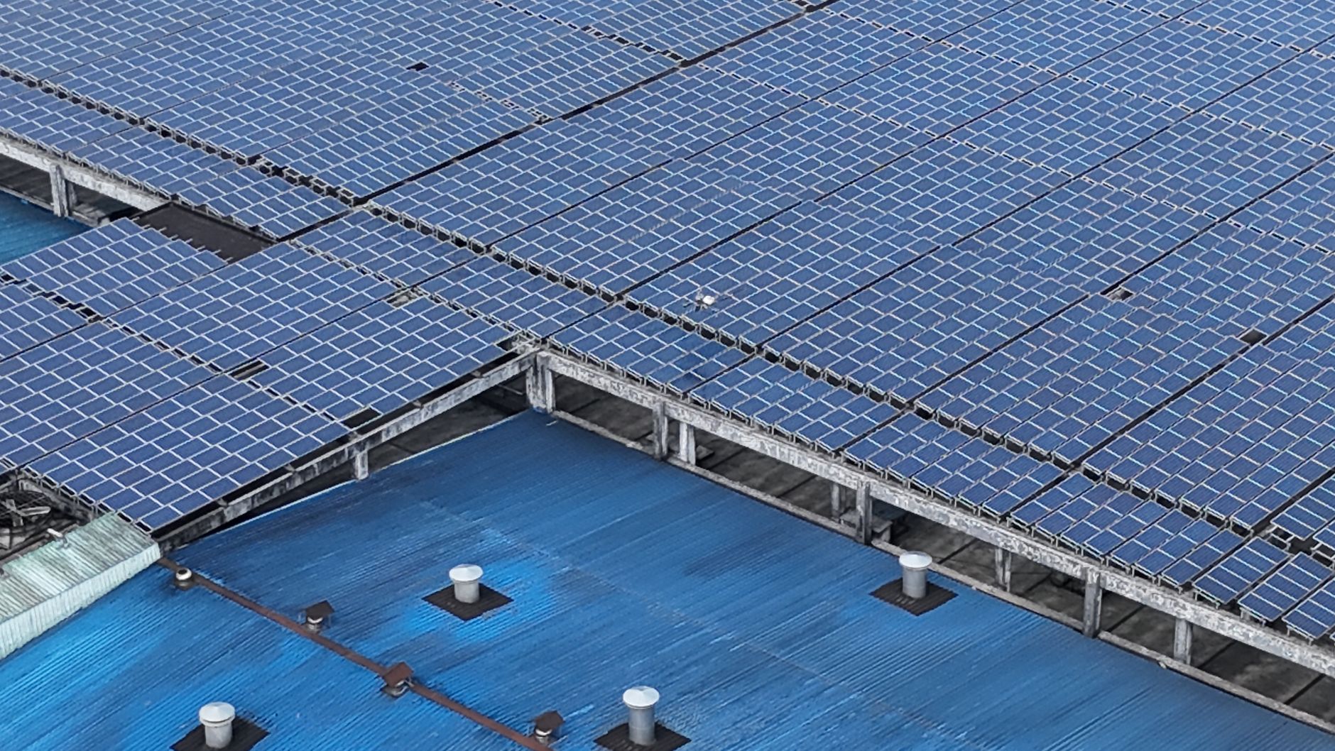 Luftaufnahme von Solarmodulen auf einem Industriedach – Ballast statt Dachdurchdringung hält die Anlage auf der Abdichtung